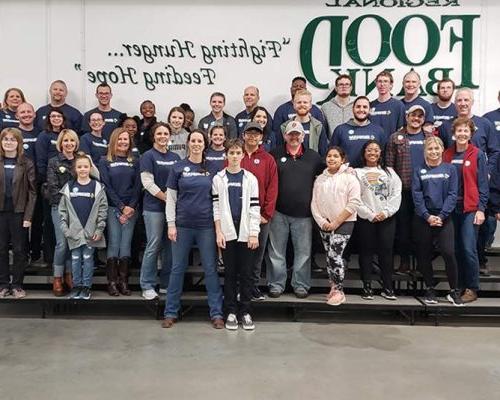 一大群Benham团队成员聚集在一起拍照，他们在俄克拉何马州地区食品银行做志愿者